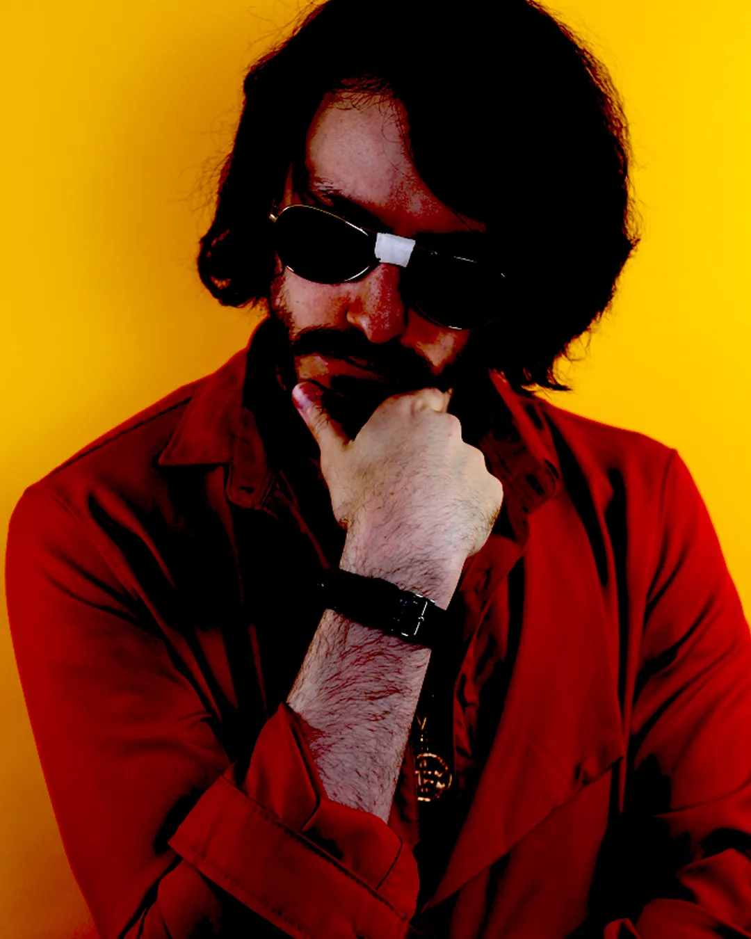 Rito Rhymes with his hand on his chin wearing sunglasses