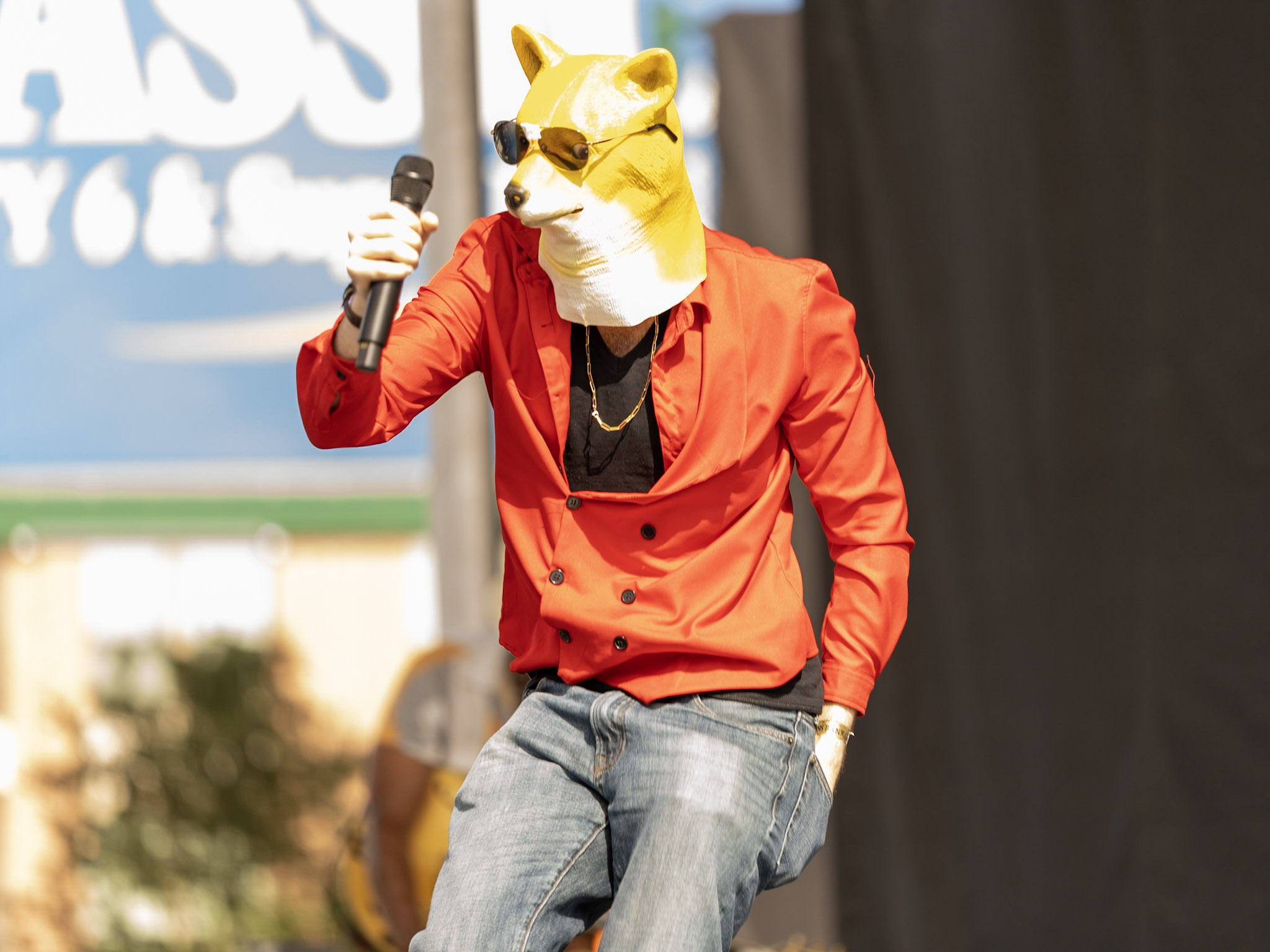 Rito wearing a dog mask performing rap on stage with a microphone and a red shirt